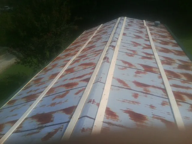 Rusted metal roof panels with new wood purlins before replacement in Milton