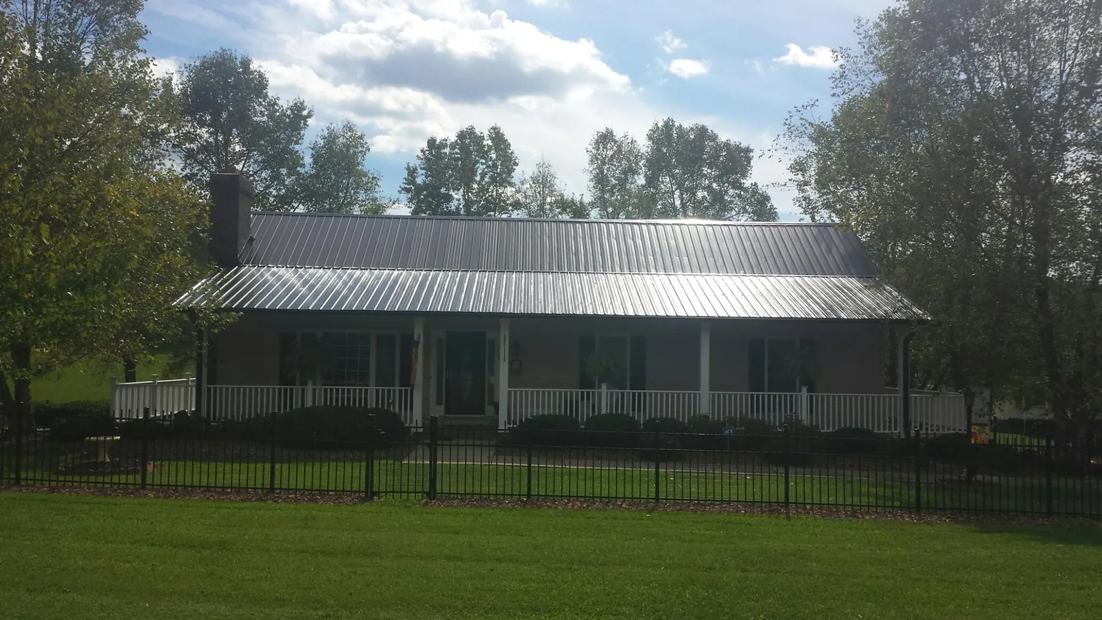 Gray metal roof on a brick ranch with a full width front porch — Gutter Guard Installation work by our crew in Milton
